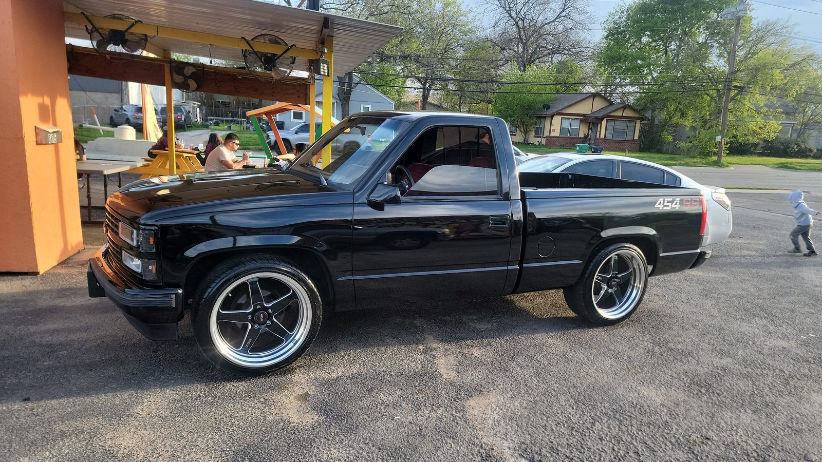 A black Chevrolet pickup with polished wheels parked in front of an outdoor patio